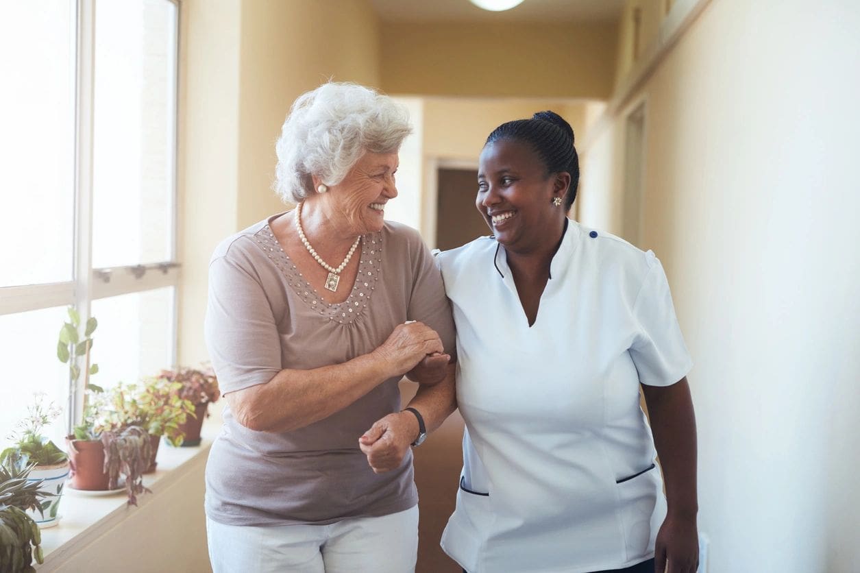 Elderly woman and caregiver sharing a joyful moment indoors.