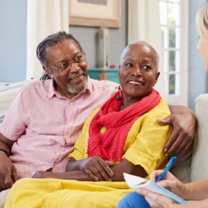 Elderly couple smiling and talking with a healthcare professional.