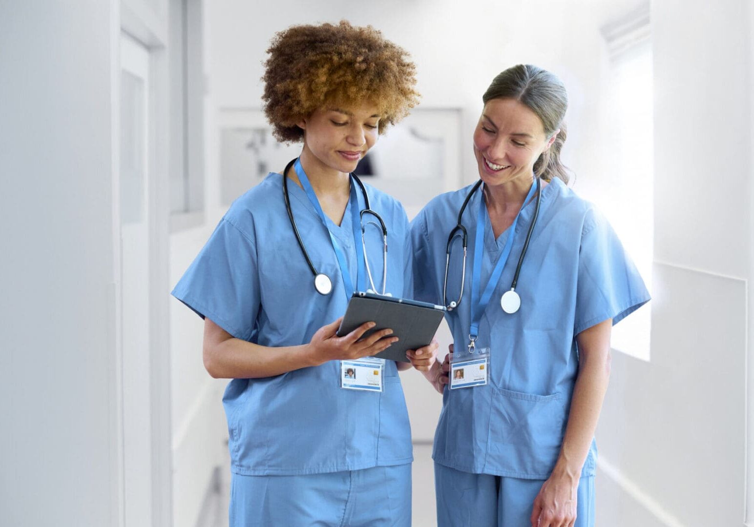 Two nurses discussing patient information in hallway.
