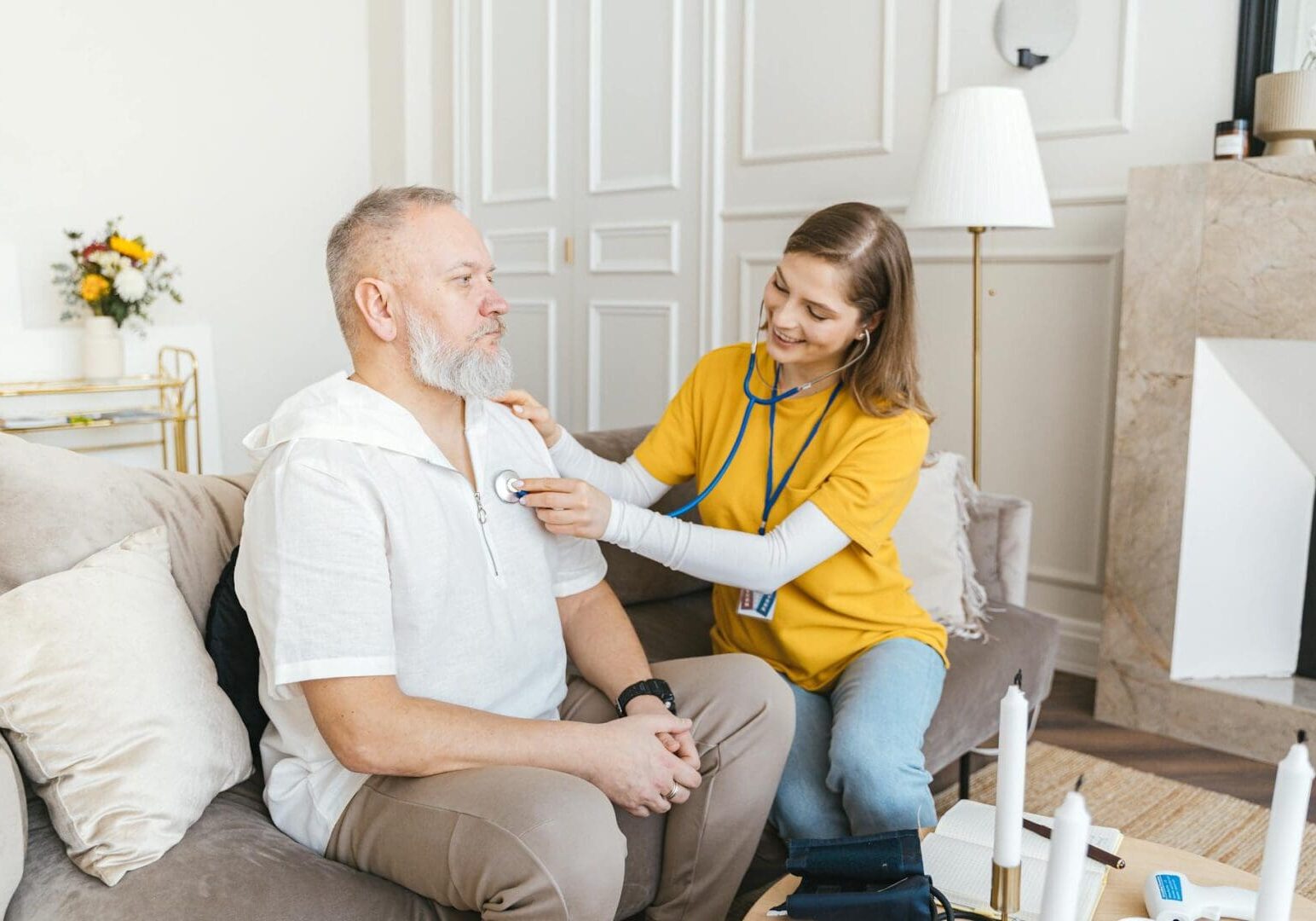 A healthcare worker checks a man's blood pressure at home.